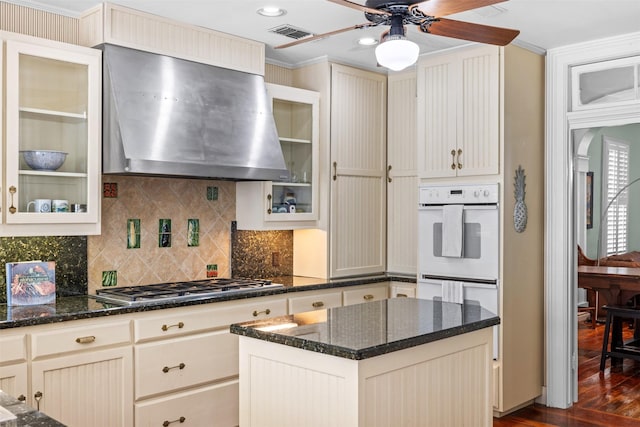 kitchen with dark stone countertops, stainless steel gas cooktop, exhaust hood, and crown molding