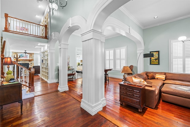 living room featuring ornate columns, hardwood / wood-style flooring, a fireplace, and ornamental molding