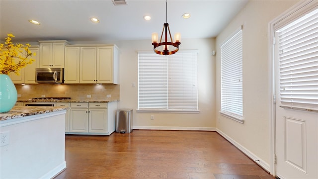 kitchen featuring light stone countertops, a wealth of natural light, appliances with stainless steel finishes, hanging light fixtures, and a chandelier