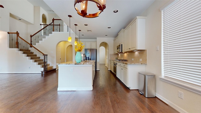 kitchen with white cabinetry, stainless steel appliances, an inviting chandelier, an island with sink, and hanging light fixtures