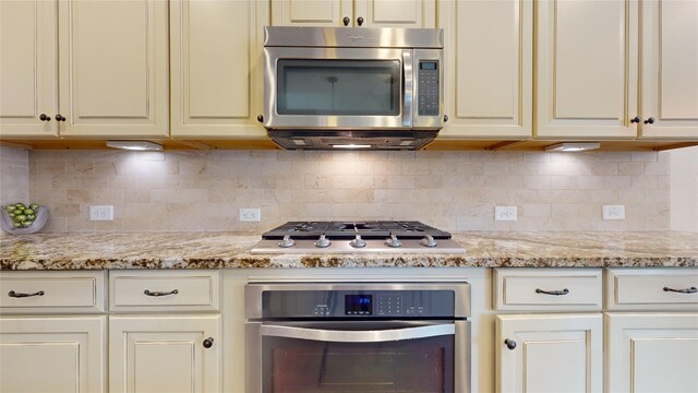 kitchen with stainless steel appliances, backsplash, and light stone countertops