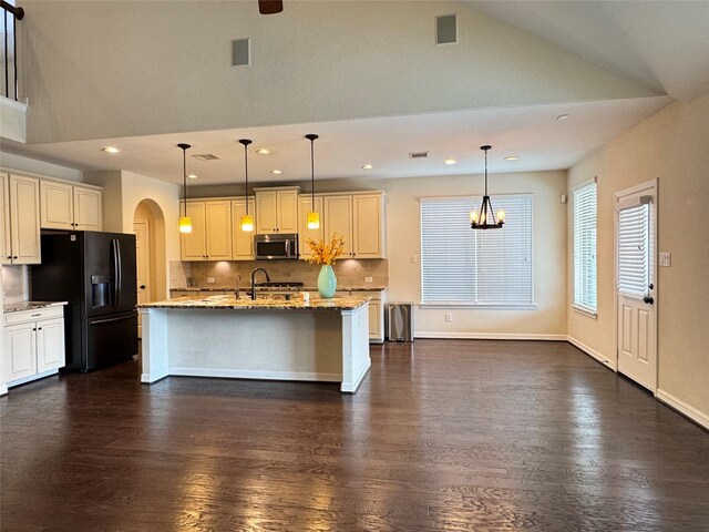 kitchen featuring a kitchen island with sink, black refrigerator with ice dispenser, tasteful backsplash, and pendant lighting