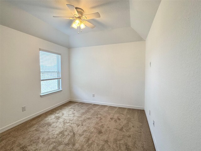 carpeted empty room featuring ceiling fan, lofted ceiling, and a tray ceiling