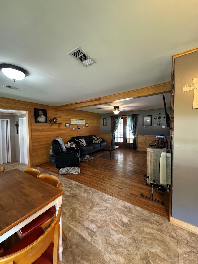 living room featuring wood walls, french doors, and tile patterned floors