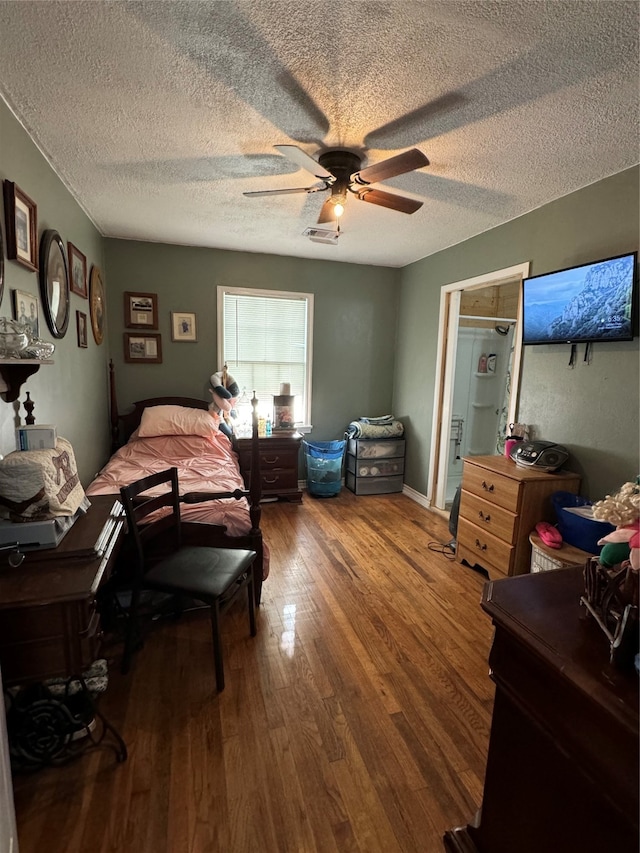 bedroom with a textured ceiling, ceiling fan, and hardwood / wood-style floors