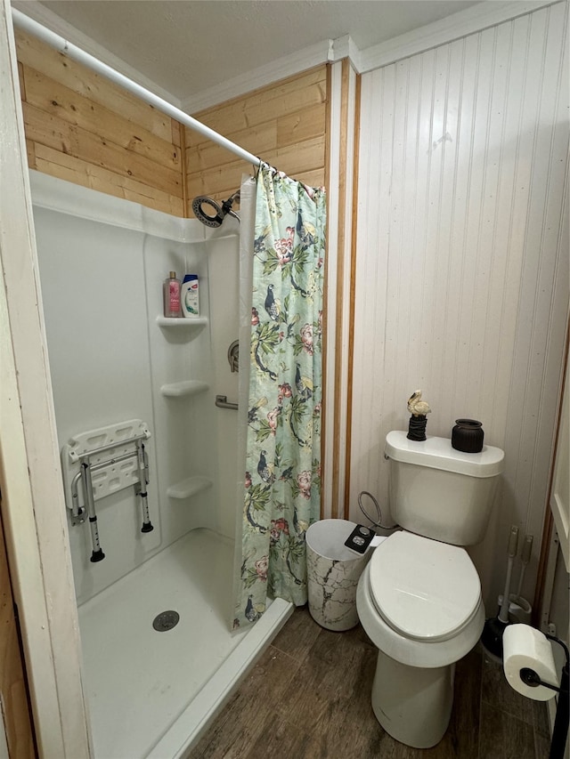 bathroom with wooden walls, hardwood / wood-style floors, toilet, a shower with curtain, and ornamental molding