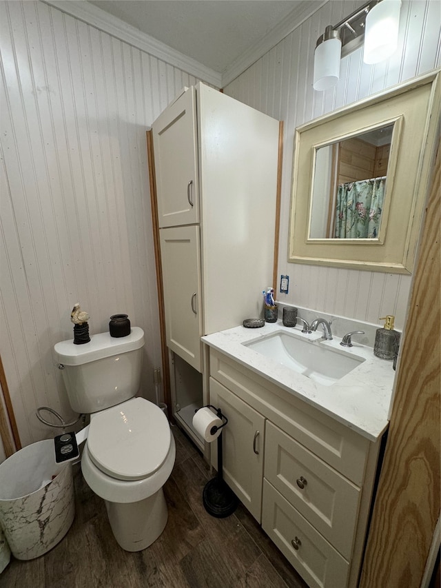 bathroom featuring vanity, crown molding, hardwood / wood-style flooring, and toilet