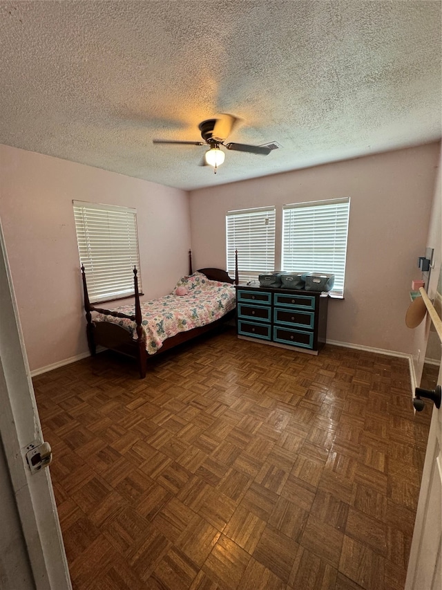 bedroom with a textured ceiling, ceiling fan, and dark parquet floors