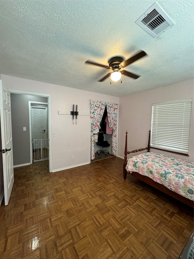 unfurnished bedroom featuring a textured ceiling, ceiling fan, and dark parquet floors