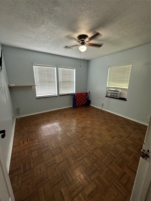 spare room featuring ceiling fan, a healthy amount of sunlight, and dark parquet floors