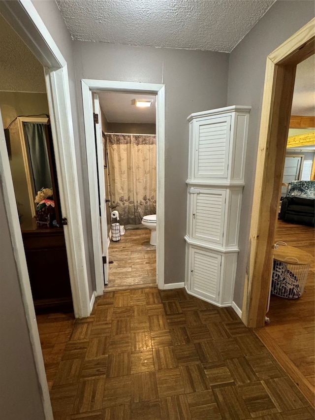 corridor featuring a textured ceiling and dark parquet floors