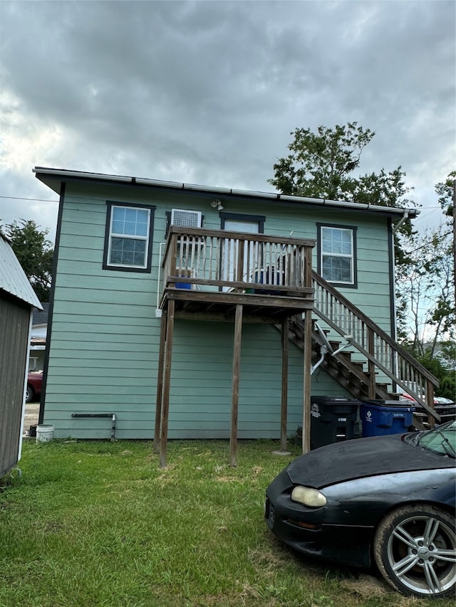 rear view of house featuring a wooden deck and a yard