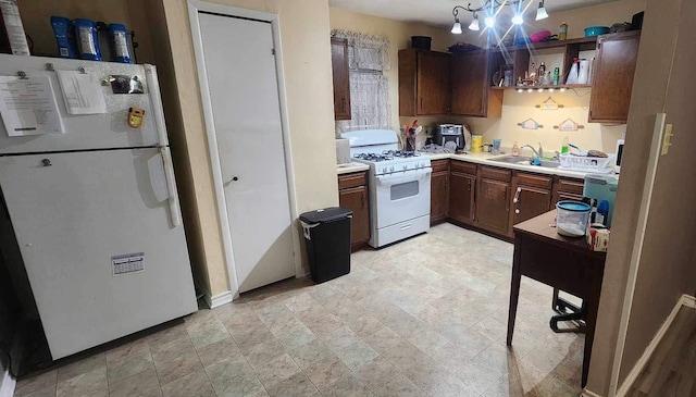 kitchen with white appliances, an inviting chandelier, dark brown cabinets, sink, and light tile patterned floors