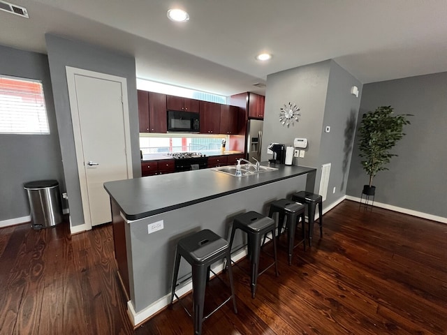 kitchen featuring a breakfast bar area, kitchen peninsula, dark hardwood / wood-style flooring, sink, and stainless steel refrigerator with ice dispenser