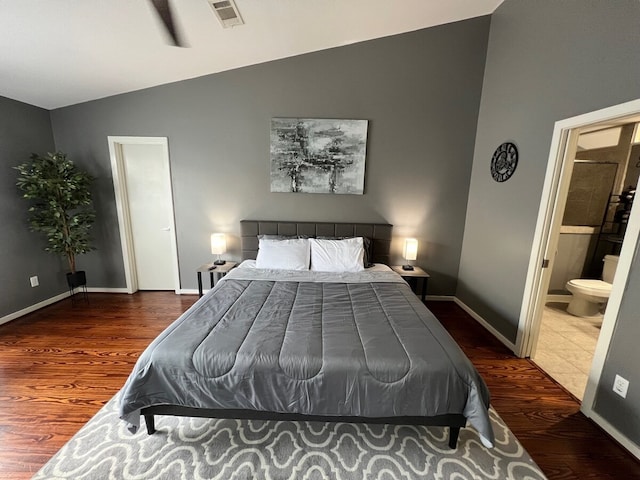 bedroom featuring ensuite bath, vaulted ceiling, and dark wood-type flooring