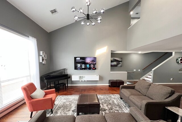 living room featuring high vaulted ceiling, hardwood / wood-style floors, a wealth of natural light, and an inviting chandelier