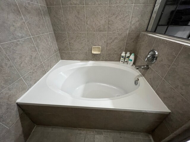 bathroom featuring tile walls, tiled bath, and tile patterned flooring