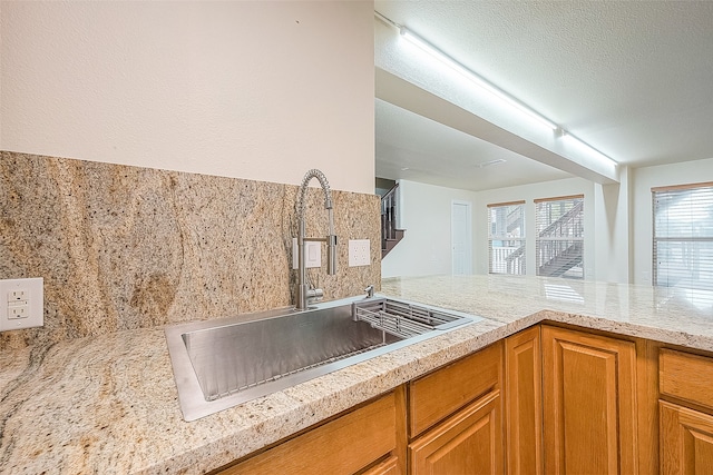 kitchen with sink, a textured ceiling, and light stone countertops