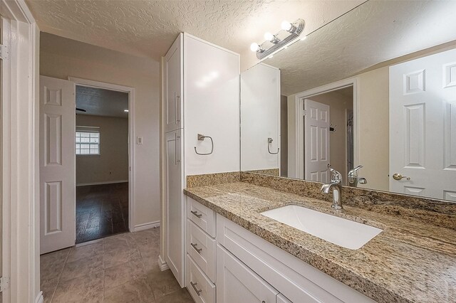 bathroom with vanity, a textured ceiling, and tile patterned flooring