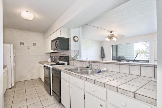 kitchen featuring white cabinetry, brick wall, black appliances, tile counters, and tasteful backsplash