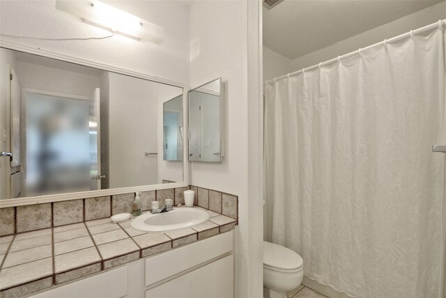 bathroom featuring tile patterned floors, walk in shower, toilet, vanity, and a textured ceiling