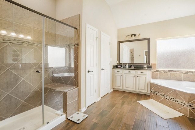 bathroom with vaulted ceiling, shower with separate bathtub, and vanity