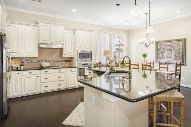 kitchen featuring a center island with sink, appliances with stainless steel finishes, decorative backsplash, pendant lighting, and sink