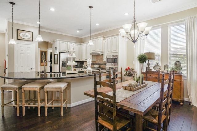 dining space featuring dark hardwood / wood-style flooring, sink, crown molding, and a notable chandelier