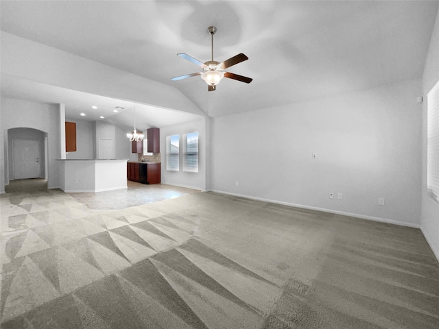 unfurnished living room featuring ceiling fan with notable chandelier, vaulted ceiling, and light colored carpet