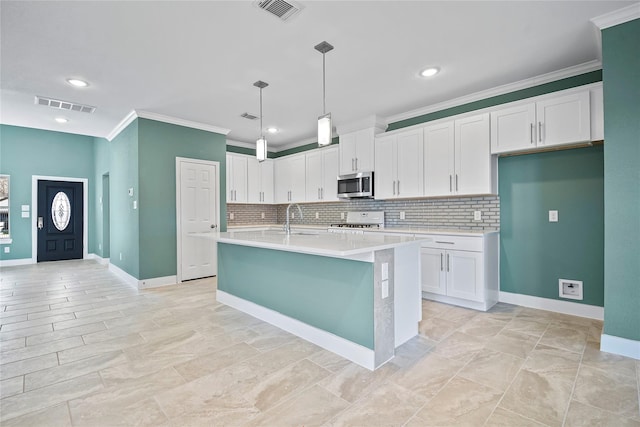 kitchen featuring pendant lighting, white cabinetry, sink, stove, and a kitchen island with sink