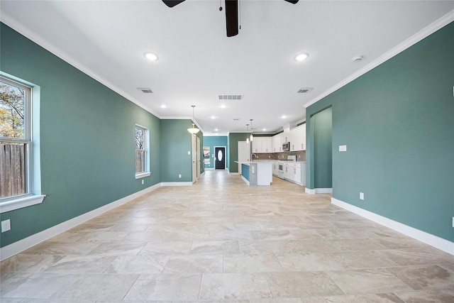 unfurnished living room with ornamental molding, sink, and ceiling fan