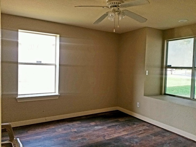 empty room with a healthy amount of sunlight, ceiling fan, and dark hardwood / wood-style flooring