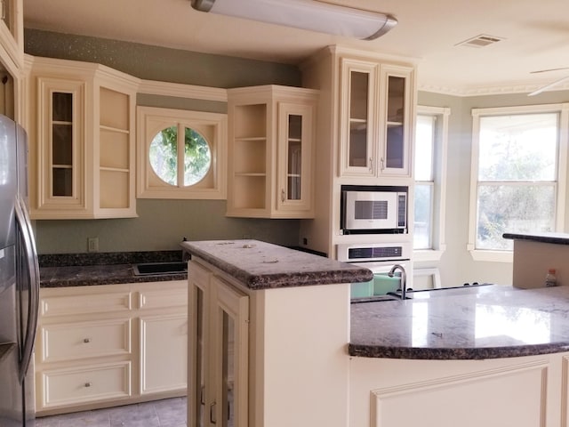 kitchen with a center island, a healthy amount of sunlight, stainless steel appliances, and dark stone counters