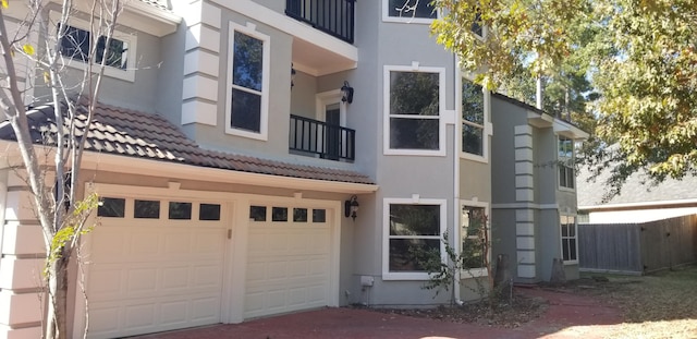 rear view of house featuring a garage and a balcony