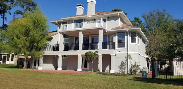 back of property with a balcony and a yard