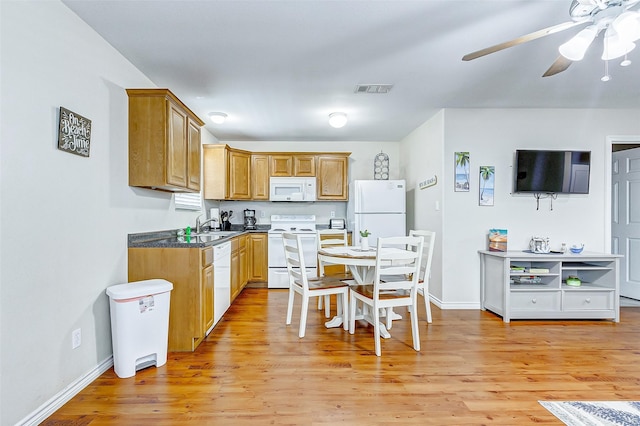 kitchen with white appliances, visible vents, dark countertops, light wood-style flooring, and a sink