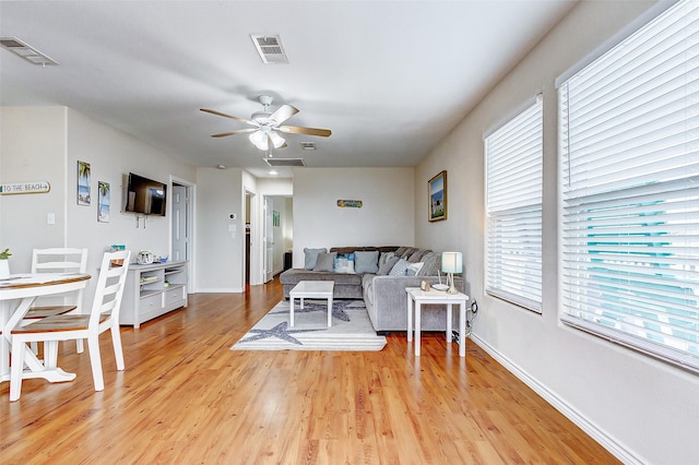 living room featuring baseboards, visible vents, and light wood finished floors