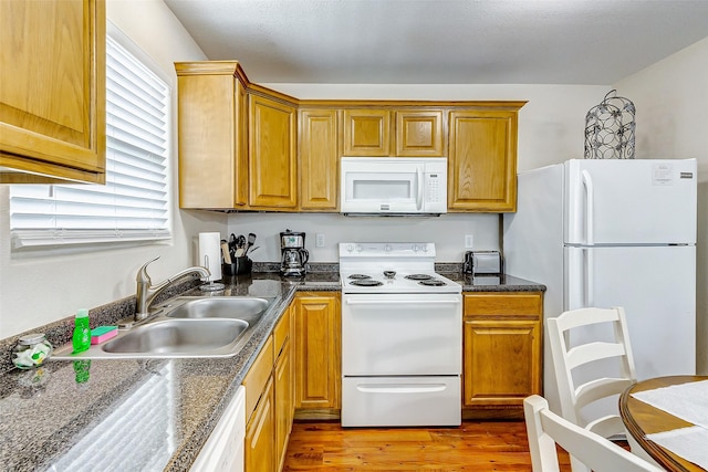 kitchen with light wood-type flooring, white appliances, brown cabinets, and a sink