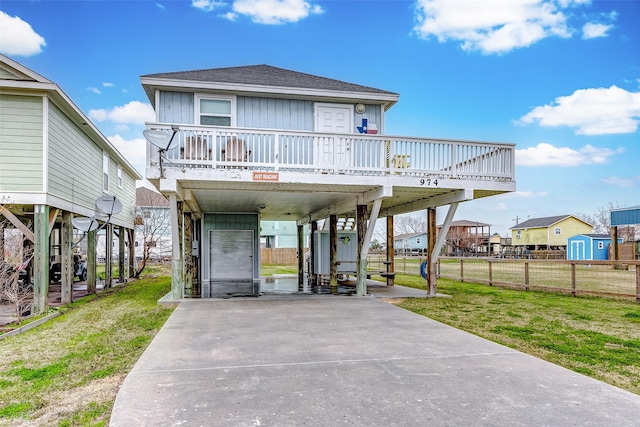 coastal inspired home featuring fence, a front lawn, a carport, and roof with shingles