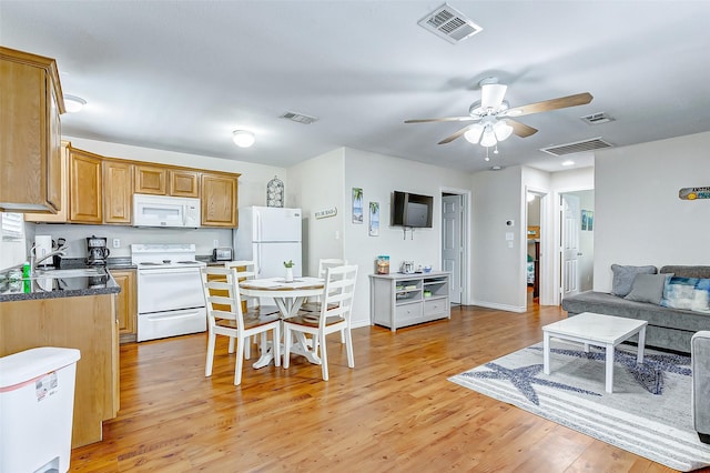 kitchen with white appliances, a sink, visible vents, light wood-type flooring, and dark countertops