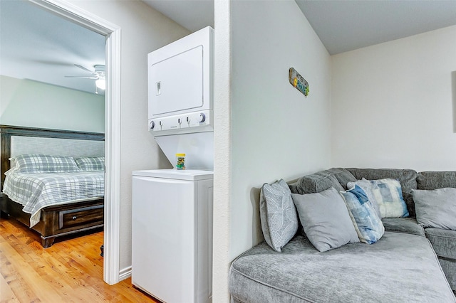 clothes washing area with laundry area, light wood-style flooring, stacked washer and clothes dryer, and a ceiling fan