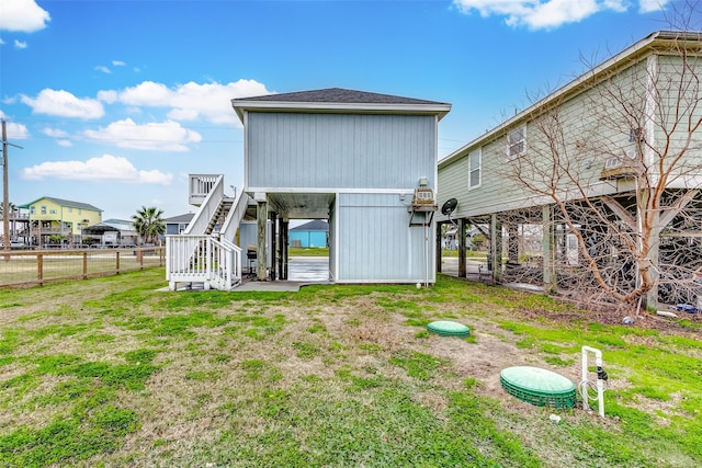 back of house with a shingled roof, fence, stairway, and a lawn