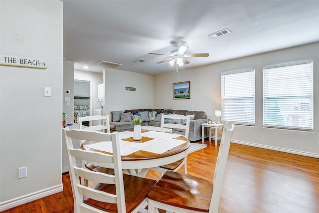 dining room featuring ceiling fan, wood finished floors, visible vents, and baseboards