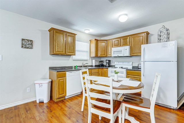 kitchen featuring dark countertops, white appliances, baseboards, and light wood finished floors