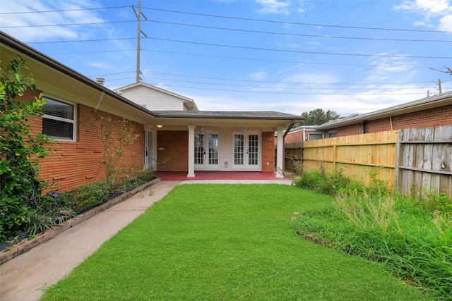 exterior space featuring a patio, a yard, and french doors