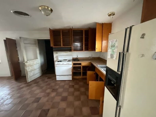 kitchen featuring dark tile patterned floors, range hood, and white appliances