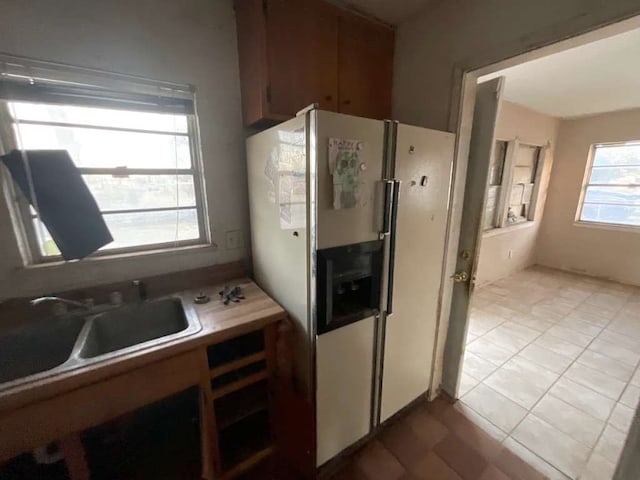 kitchen with stainless steel fridge with ice dispenser, sink, and light tile patterned floors