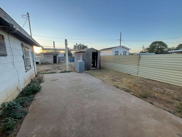 yard at dusk with a shed and a patio area