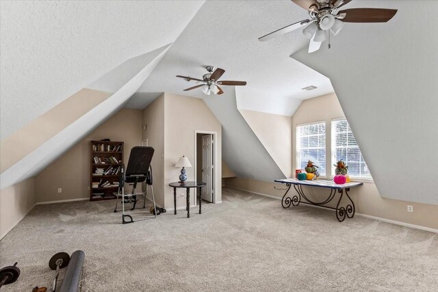 workout room featuring a textured ceiling, light colored carpet, ceiling fan, and lofted ceiling