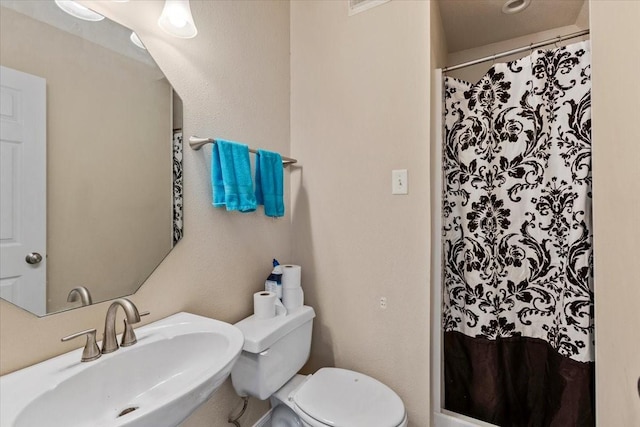 full bathroom featuring toilet, a shower with curtain, and a sink